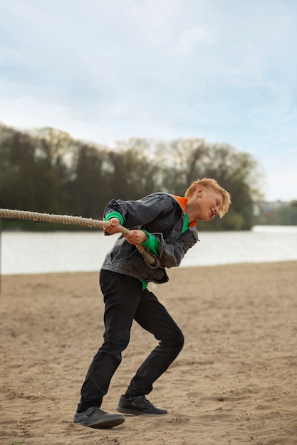 Free photo full shot boy playing tug-of-war on the beach