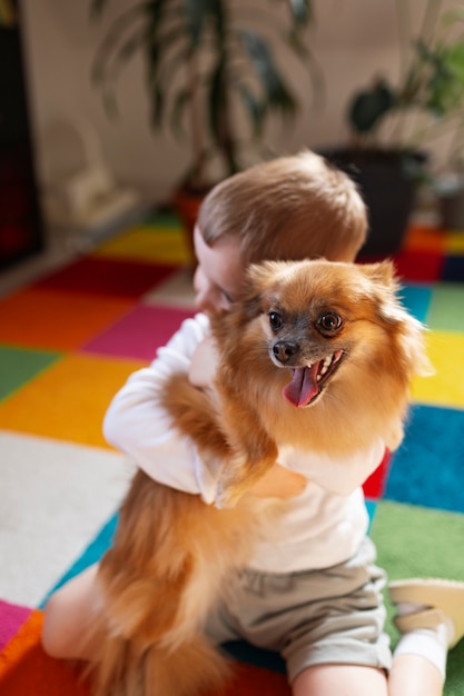 Full shot boy playing with dog indoors