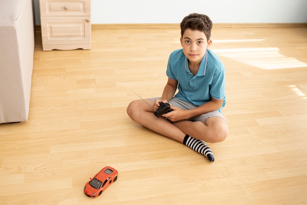 Full shot boy playing with an electric car