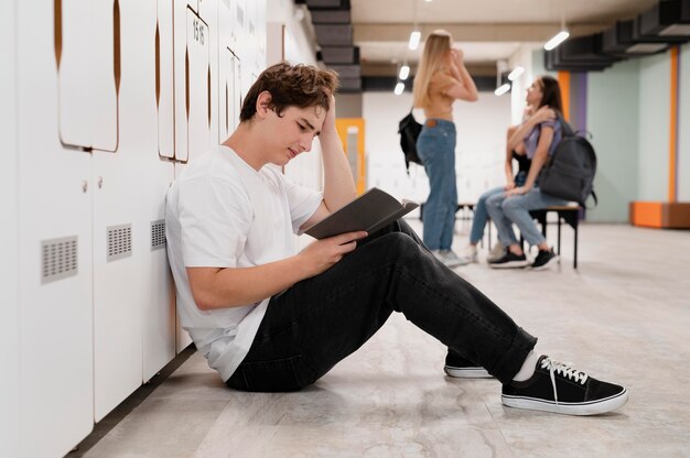 Full shot boy reading on floor