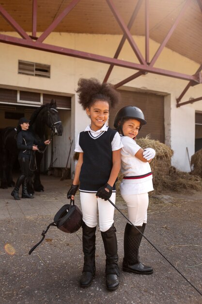 Full shot children learning to ride horses