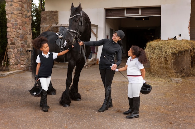 Full shot children learning to ride horses