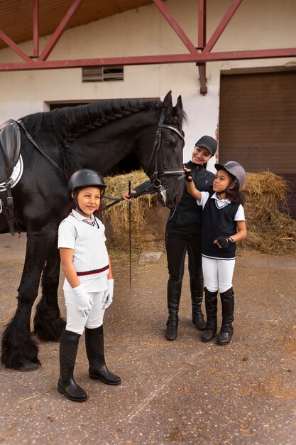 Full shot children learning to ride horses