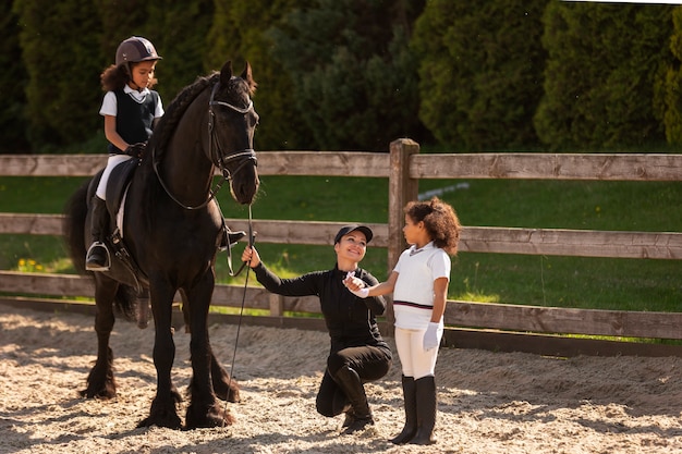 Full shot children learning to ride horses