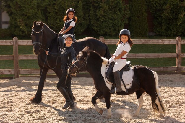 Full shot children learning to ride horses