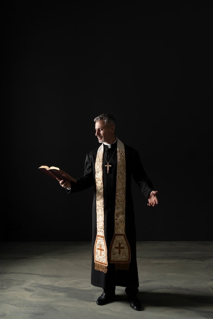 Full shot christian priest reading bible