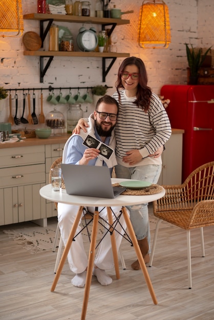 Full shot couple announcing pregnancy with laptop