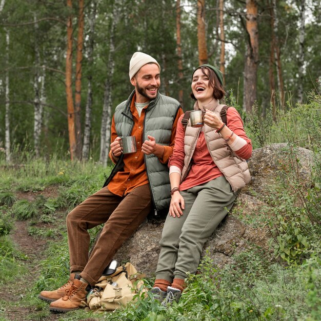 Full shot couple enjoying hot drink in nature