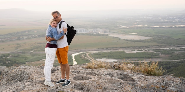 Free photo full shot couple hugging on cliff