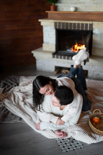 Free photo full shot couple laying by the fireplace