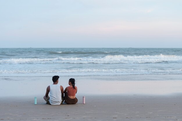 Full shot couple meditating at seaside