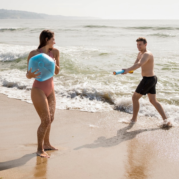 Full shot couple playing on beach