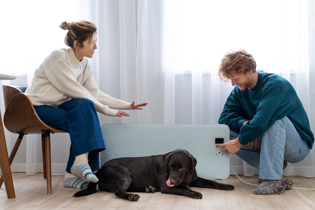 Free photo full shot couple sitting near heater