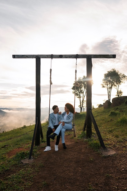 Full shot couple on swing outdoors