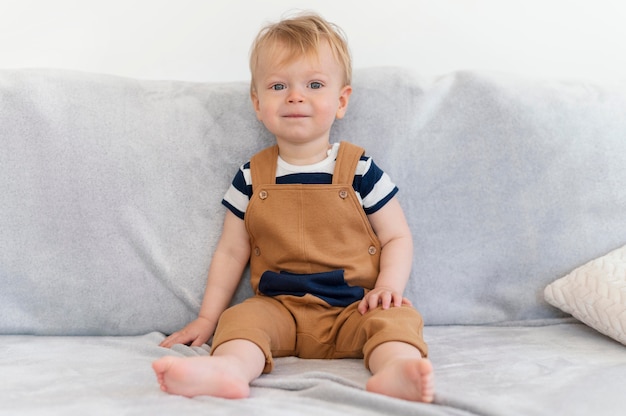 Free photo full shot cute kid sitting on couch