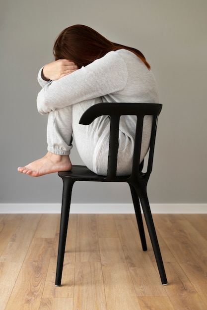 Free photo full shot depressed woman sitting on chair