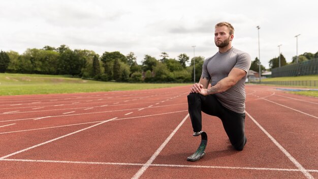 Full shot disabled man on running track stretching