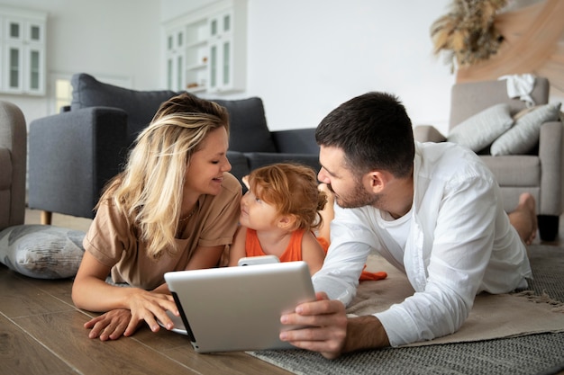 Full shot family laying on floor with tablet