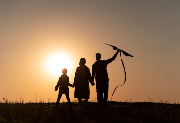 Full shot family silhouette having fun at sunset