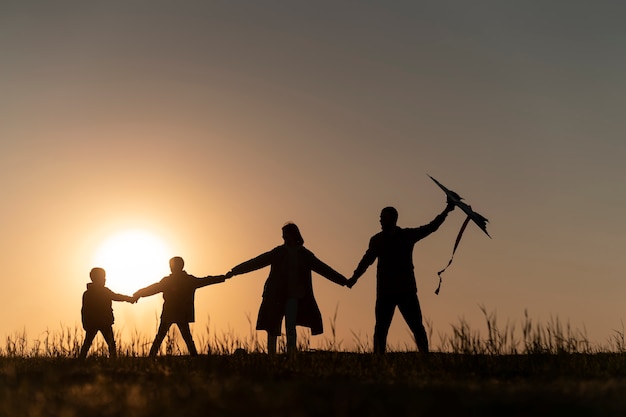 Free Photo full shot family silhouette having fun at sunset