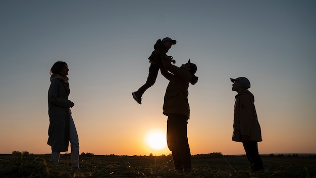 Free Photo full shot family silhouette having fun at sunset