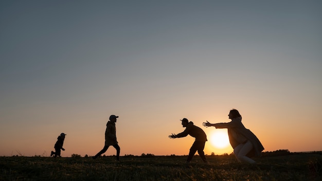 Free photo full shot family silhouette having fun at sunset