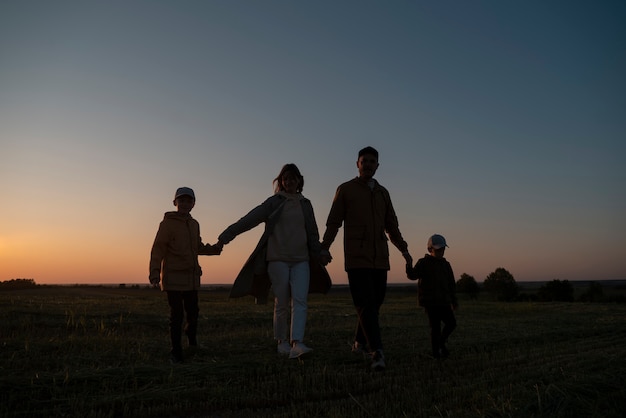 Full shot family silhouette having fun at sunset