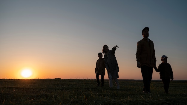 Free photo full shot family silhouette having fun at sunset