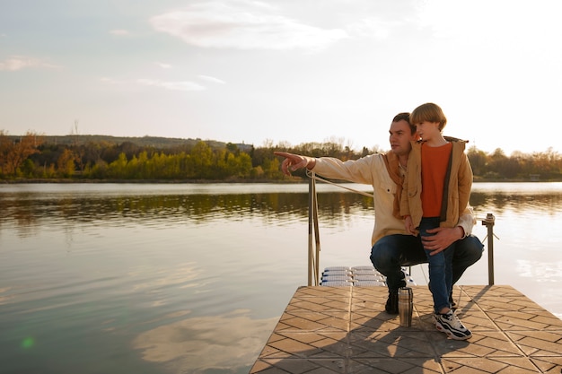 Free photo full shot father and son hanging out on a jetty