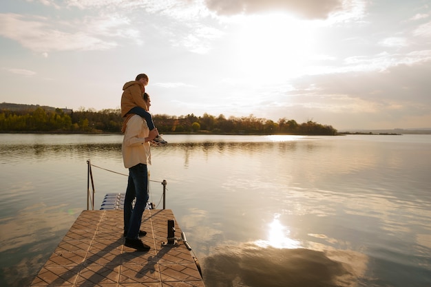 Free photo full shot father and son hanging out on a jetty