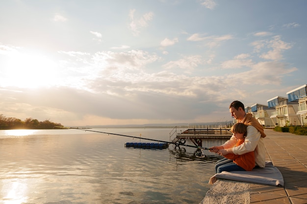 Free photo full shot father and son hanging out on a jetty