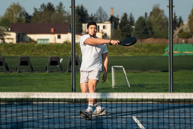 Full shot fit man playing paddle tennis