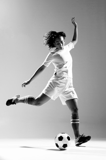 Free photo full shot fit woman kicking ball