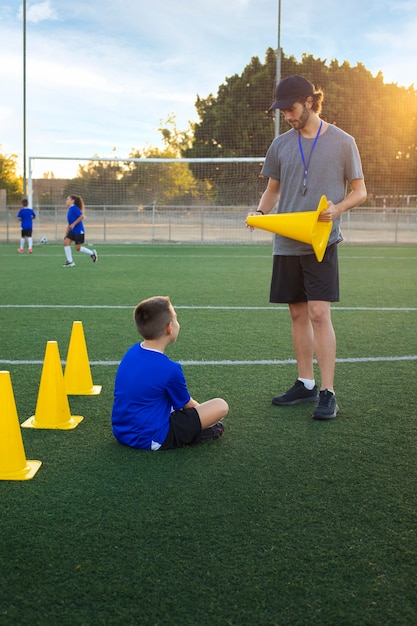 Free photo full shot football trainer teaching kids