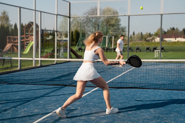 Full shot friends playing paddle tennis outdoors