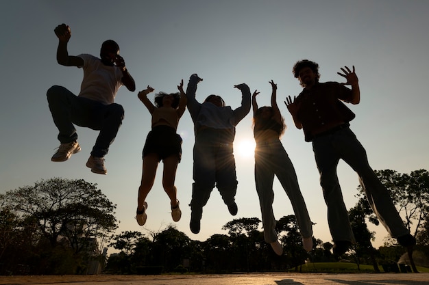 Full shot friends silhouettes jumping at sunset