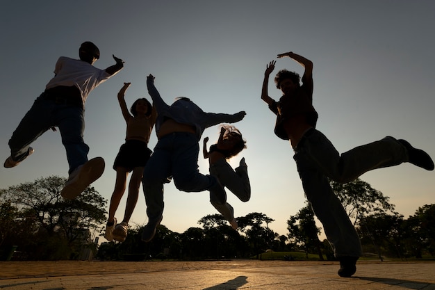 Full shot friends silhouettes jumping at sunset