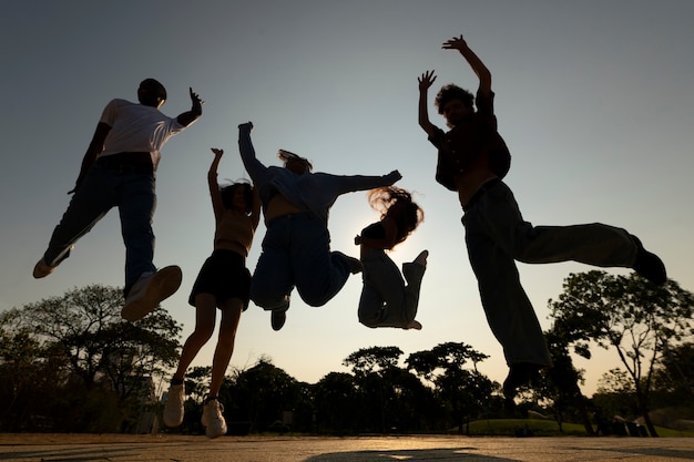 Full shot friends silhouettes jumping at sunset