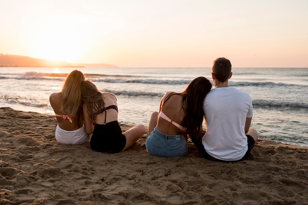 Full shot friends sitting on beach