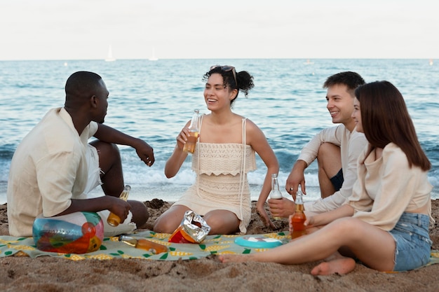 Free photo full shot friends sitting on beach