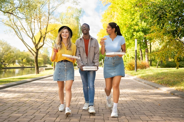 Free Photo full shot friends walking with pizza