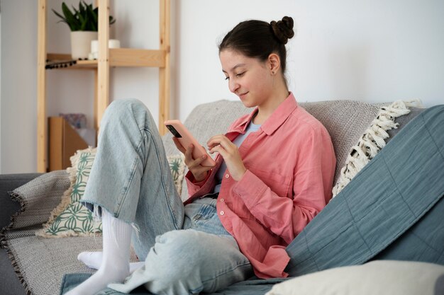 Full shot girl on couch with smartphone