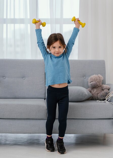 Full shot girl holding dumbbells