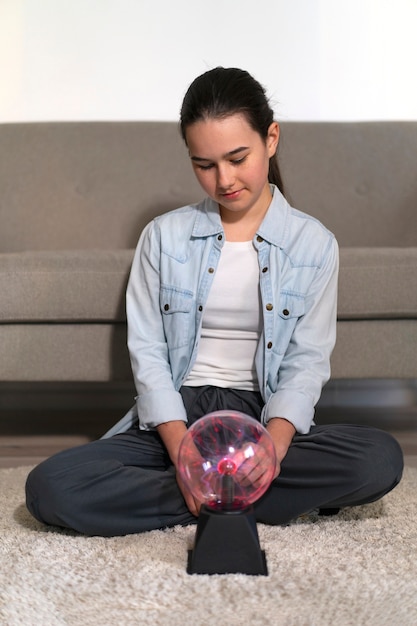 Full shot girl interacting with a plasma ball