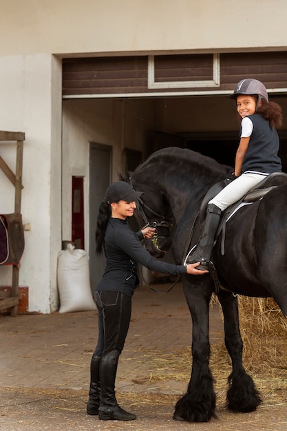 Free photo full shot girl learning to ride horse