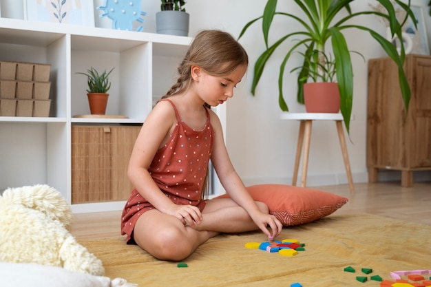 Full shot girl making puzzle at home