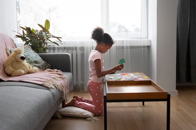 Full shot girl making puzzle on table