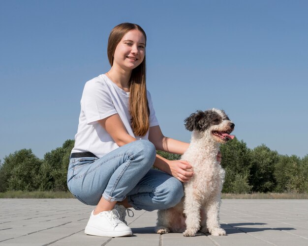 Full shot girl petting cute dog