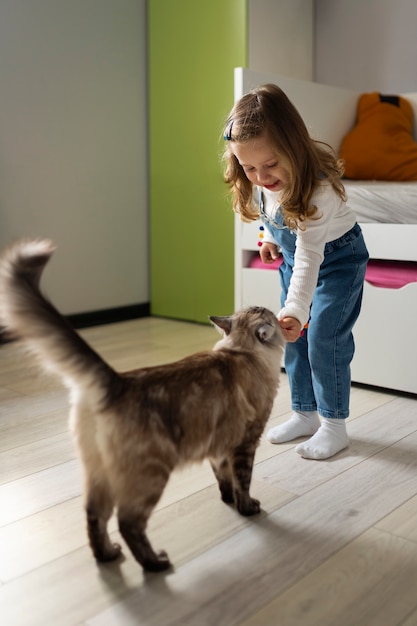 Full shot girl playing with cat