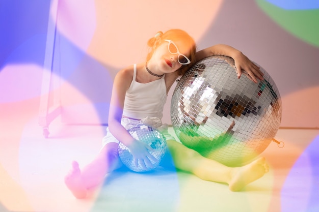 Free photo full shot girl posing with disco ball and sunglasses